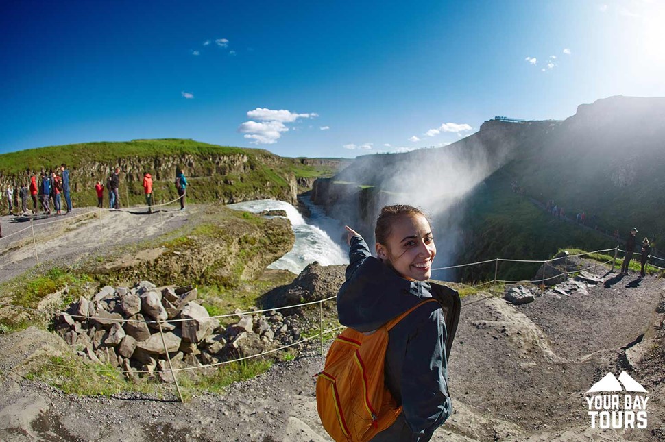 happy woman pointing at gullfoss waterfall