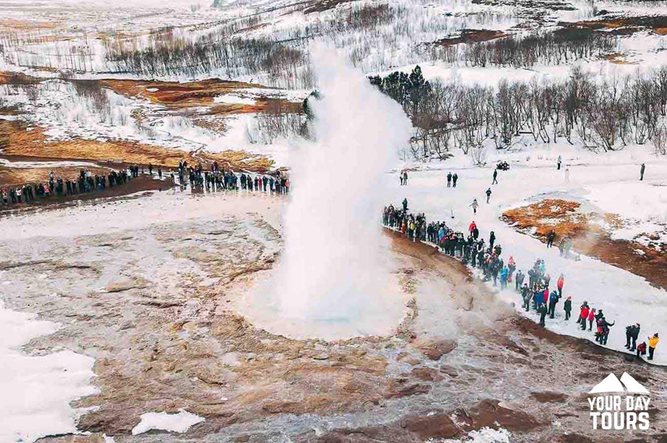 people standing by geysir in winter 