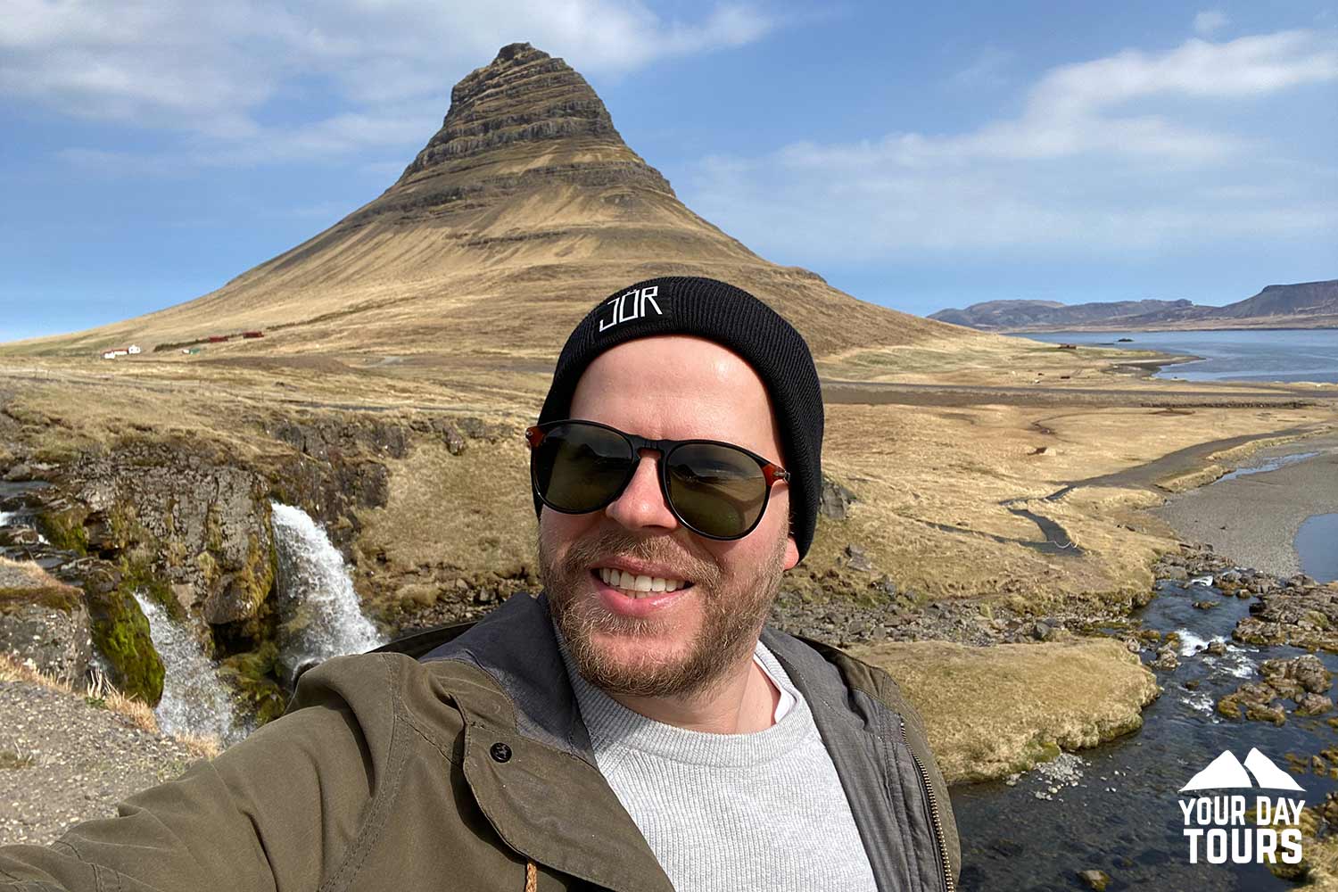 person taking a photo by kirkjufell mountain