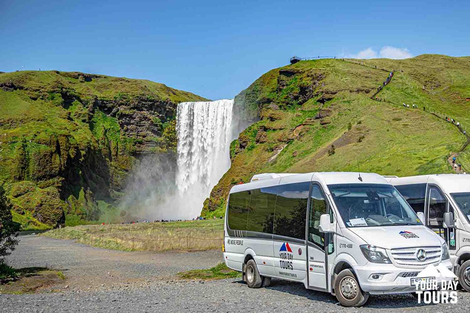 white minibuses by skogafoss waterfall in iceland 