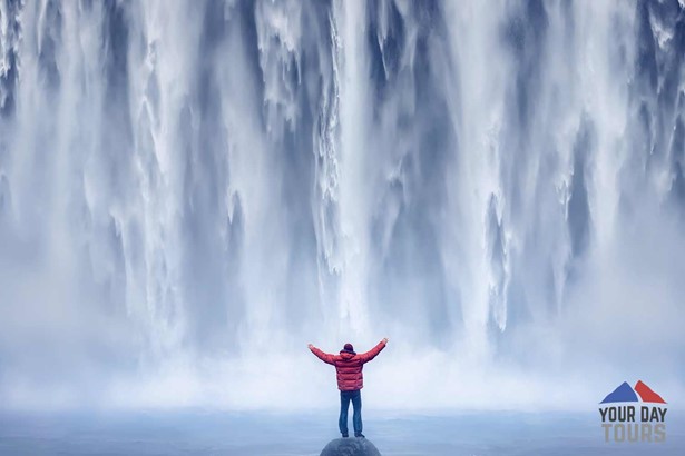 a person in front skogafoss waterfall in iceland 