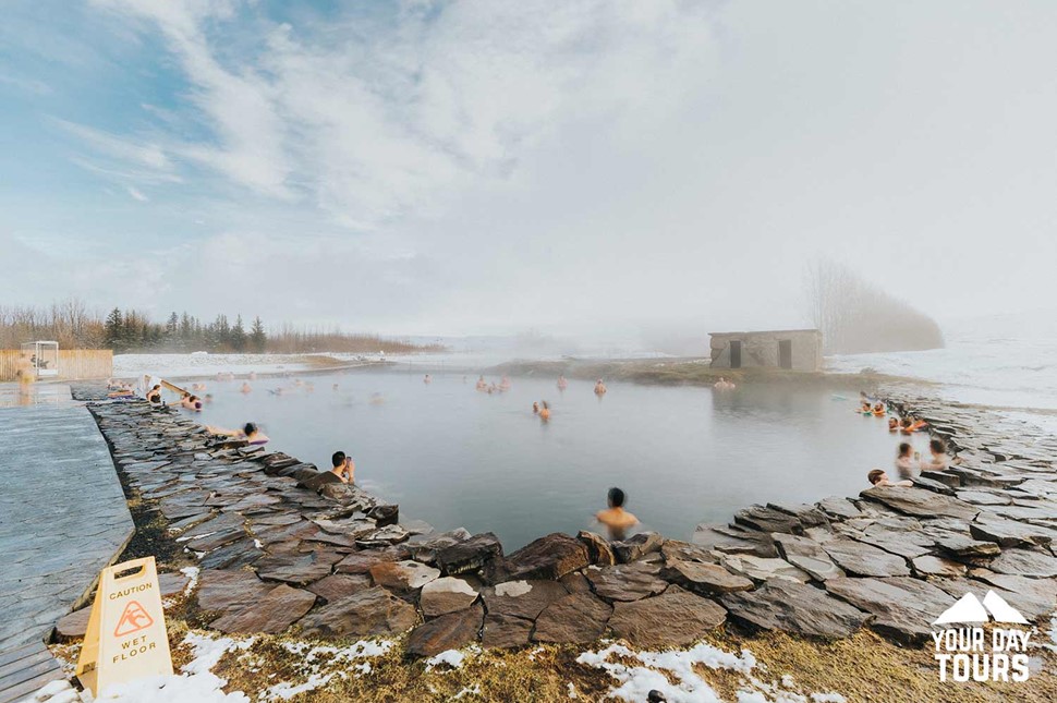 people bathing in secret lagoon in wintertime