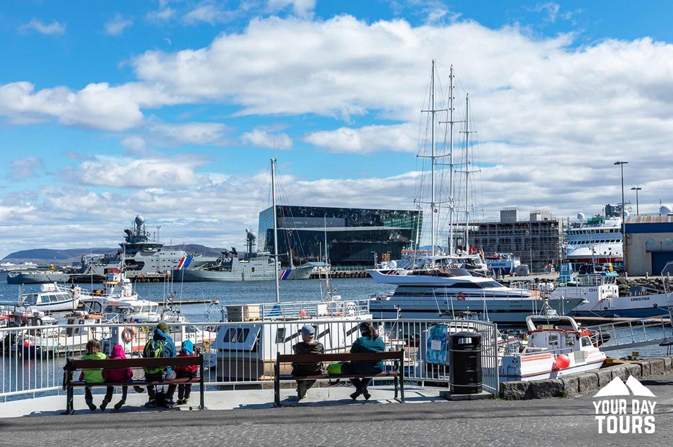 people on bench watching boats