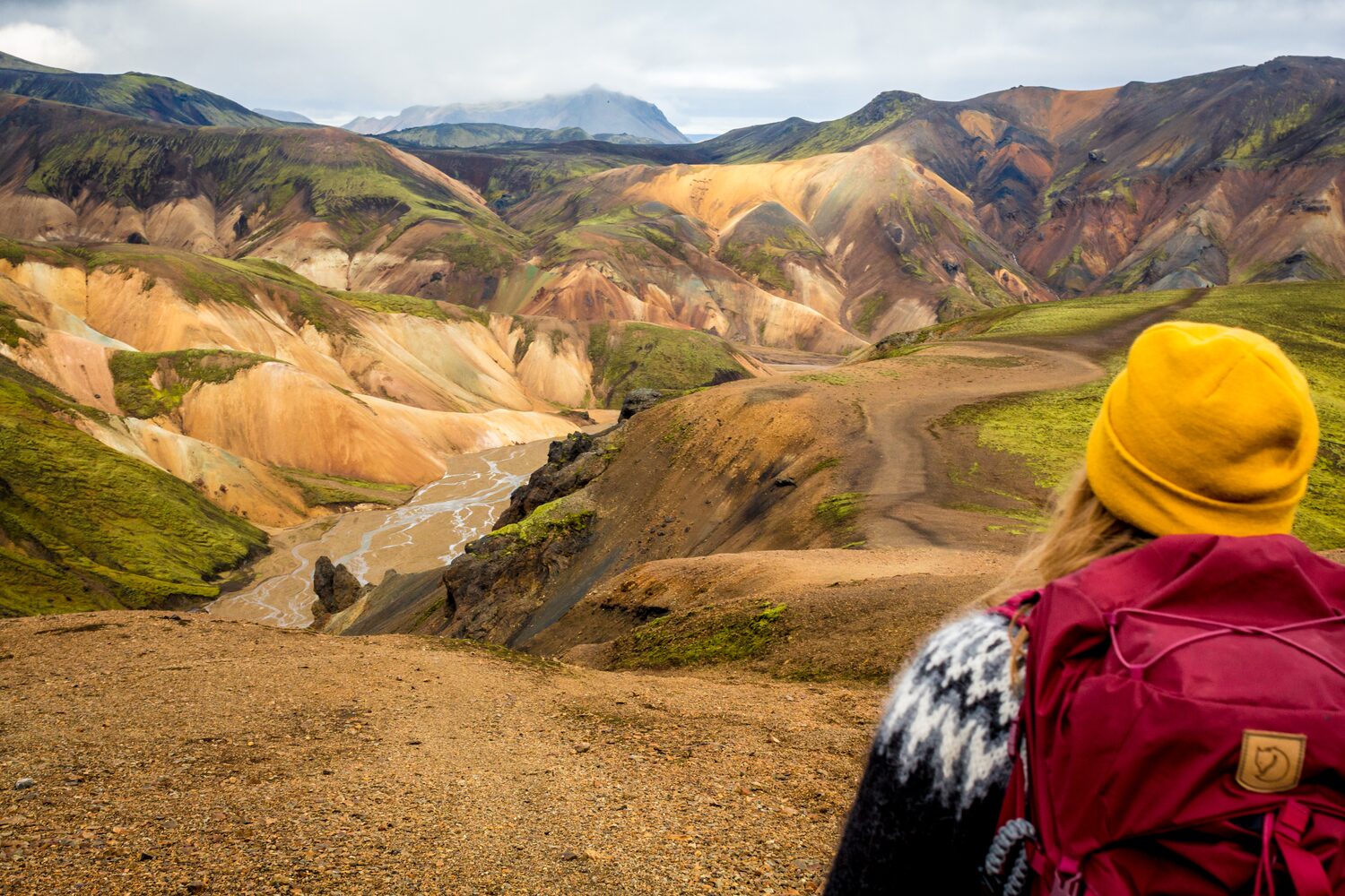 Female hiker in yellow beanie admiring views on mountain terrain Landmannalaugar hiking route 