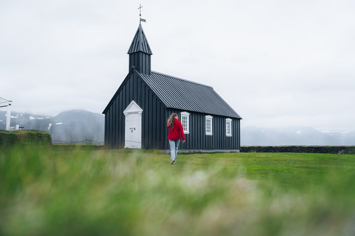 Yound female exploring Budir black church in Iceland.