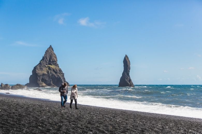 Couple walking together along Reynisfjara beach in summer.